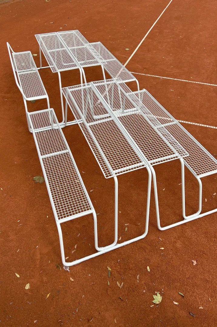 piknikové stoly Line Grid na antukovém hřišti, stohovatelný ocelový mobiliář